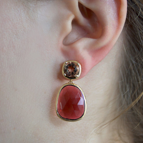 Close-up of an ear wearing a pink tourmaline stone earring with brownish-gold sunstones set in yellow gold.