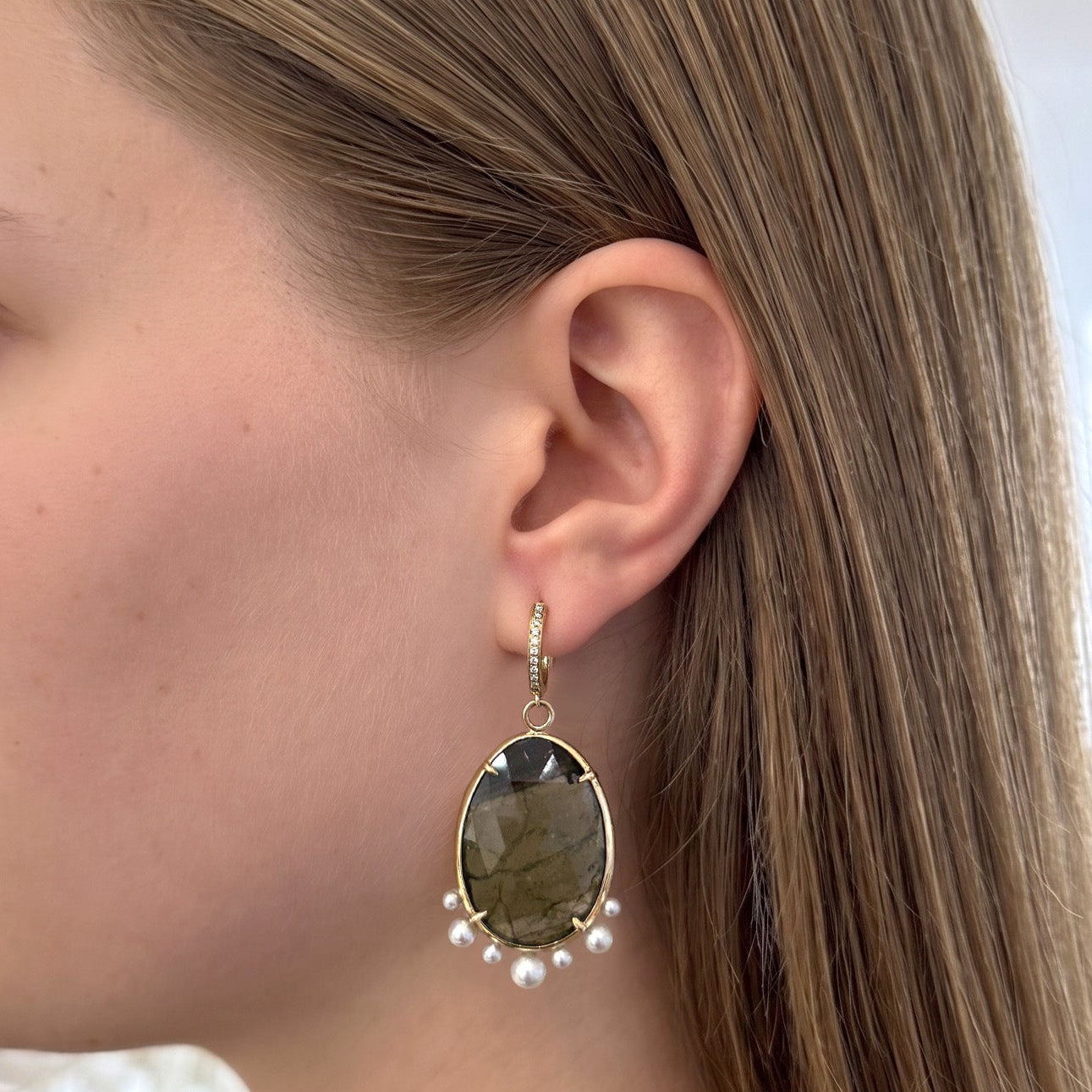 Woman wearing gold earrings with a blurred indoor background