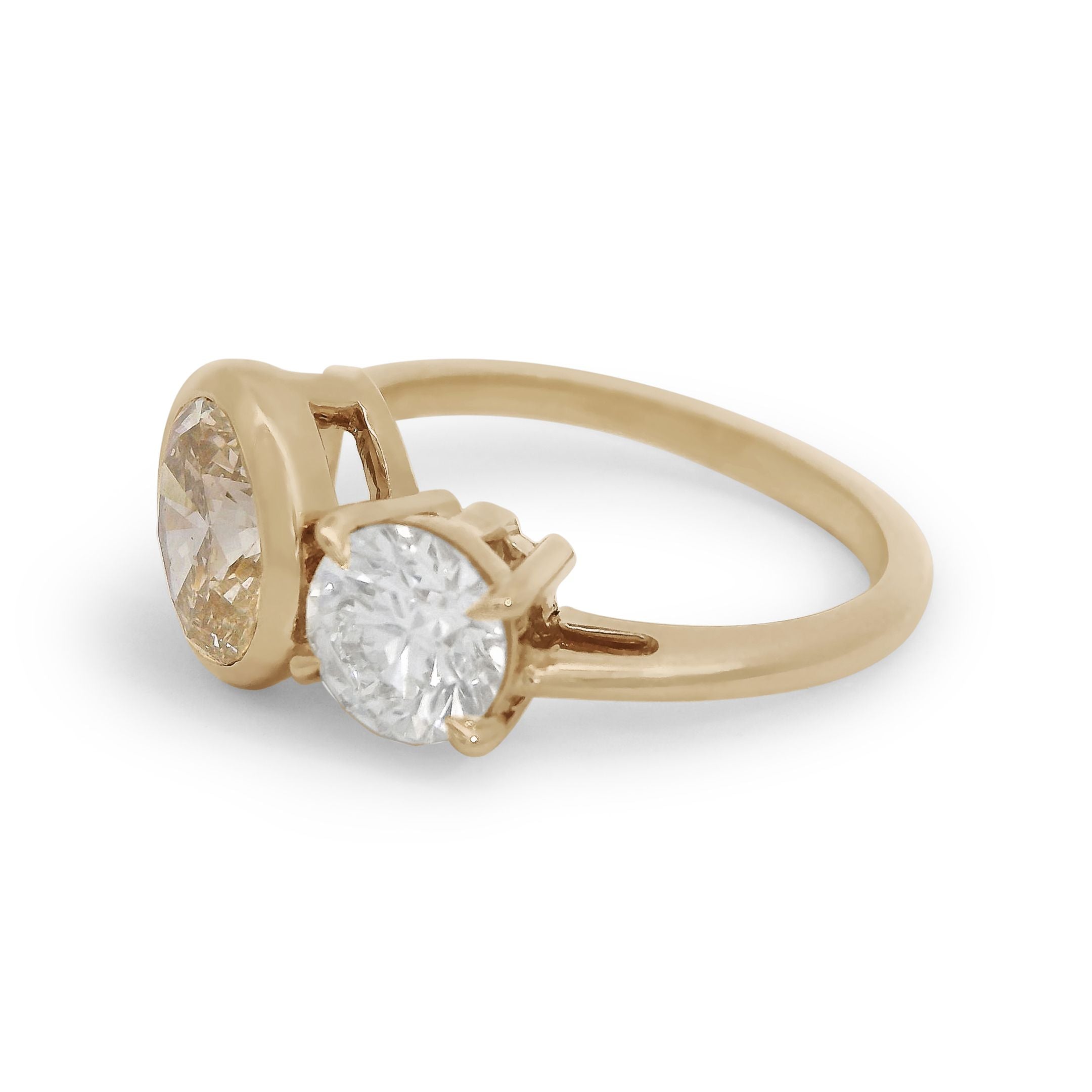 Toi et moi engagement ring featuring an oval champagne diamond and a white round diamond set in yellow gold. 