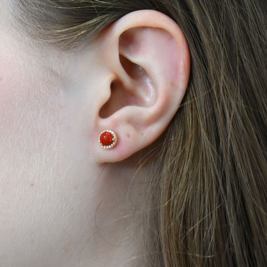 A coral earring featuring a white diamond halo on an ear. 