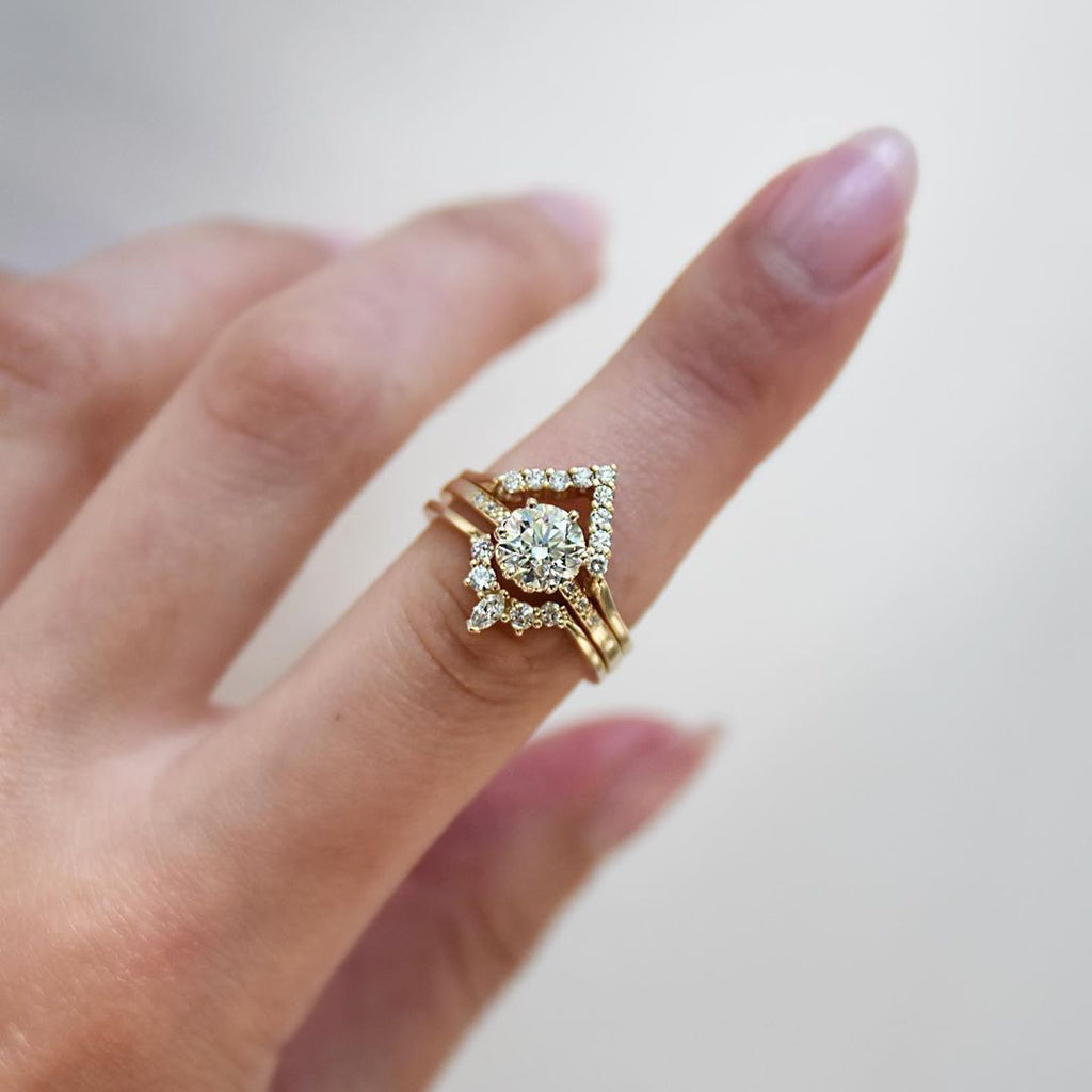 A band with 9 round white diamonds set in yellow gold above a solitaire white diamond engagment ring and a marquise white diamond band. Available in Rose Gold, Yellow Gold, White Gold.