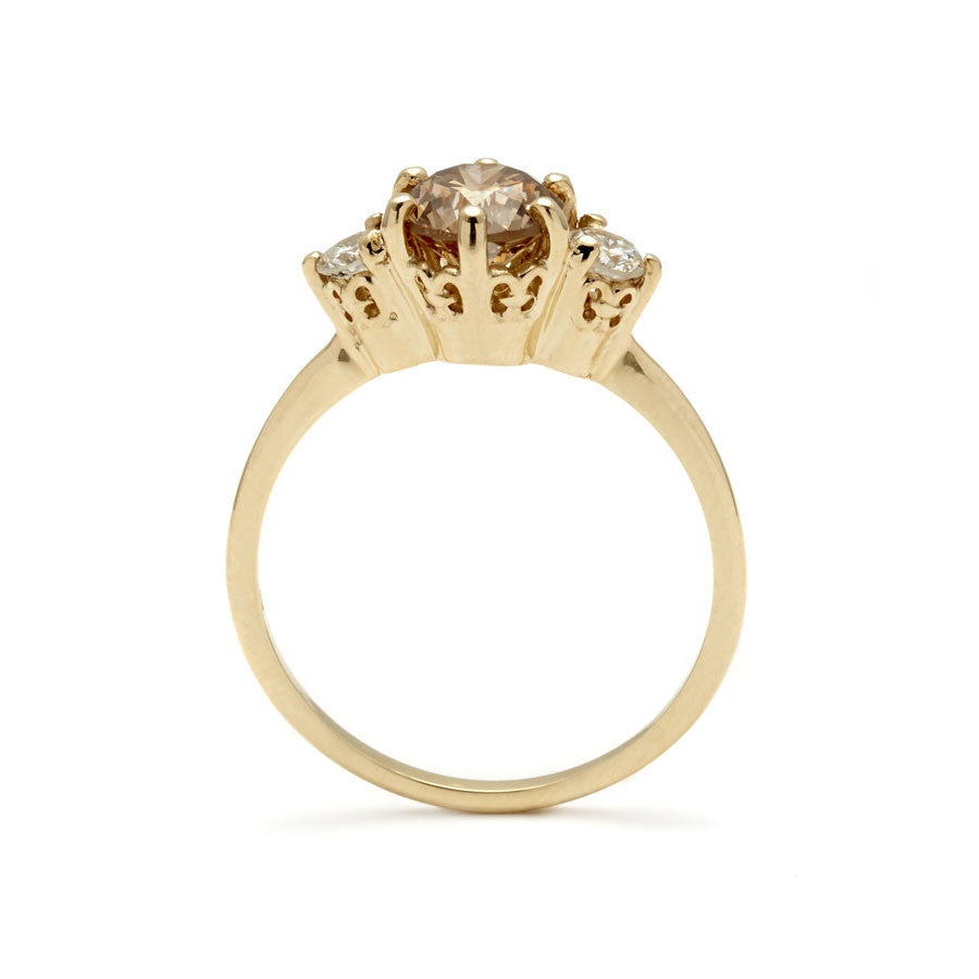 Side view of a three stone engagement ring with a round shape champagne diamond center stone with two white diamond round side stones set in yellow gold., Yellow Gold