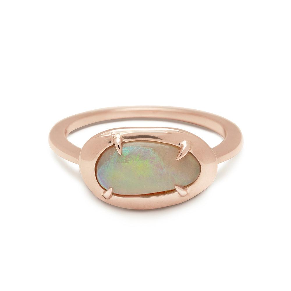 A ring with an oval opal center set in bezel with claw prongs in rose gold.