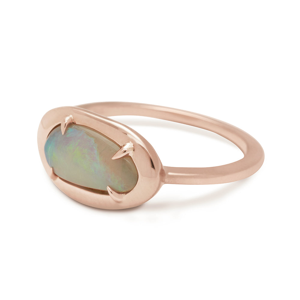 Angled view of a ring with an oval opal center set in bezel with claw prongs in rose gold.