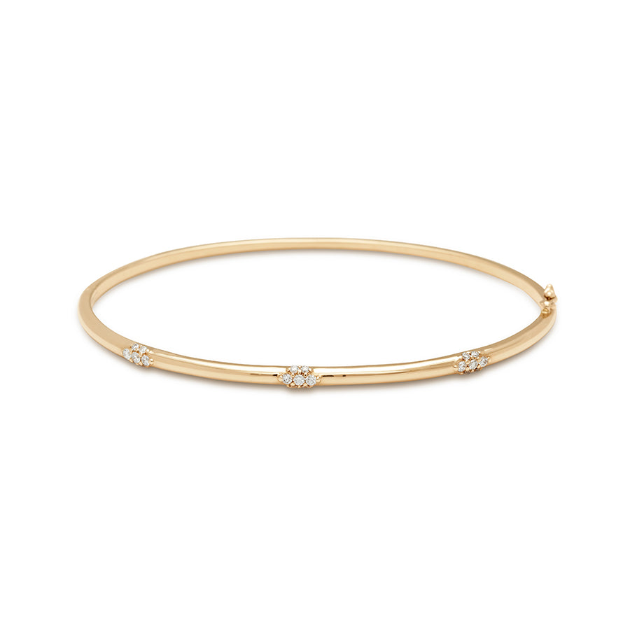 A yellow gold bangle with three sets of white diamond clusters surrounding it.