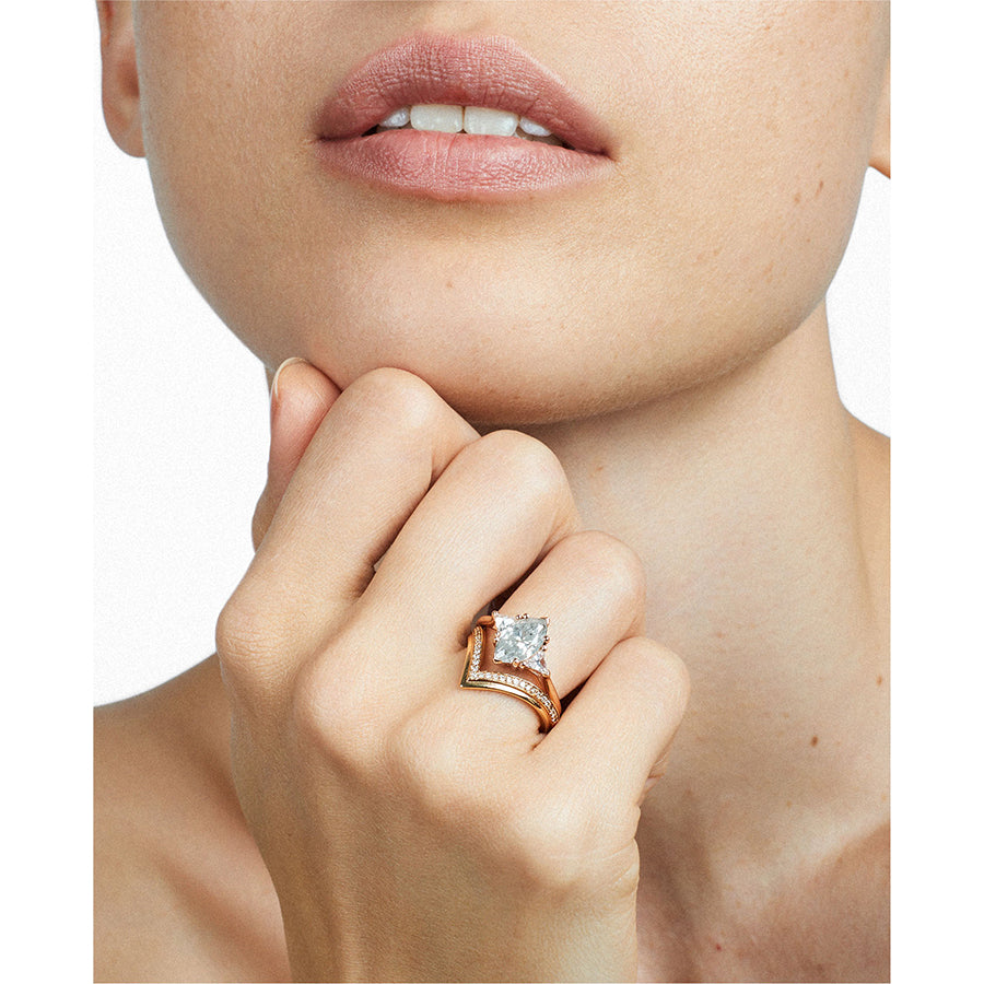 A three stone engagement ring with a marquise shape grey diamond center stone with two white diamond trillion side stones set in rose gold stacked above a diamond dusted chrysalis shaped band on a light-complexion left hand., White Gold, Rose Gold, Yellow Gold