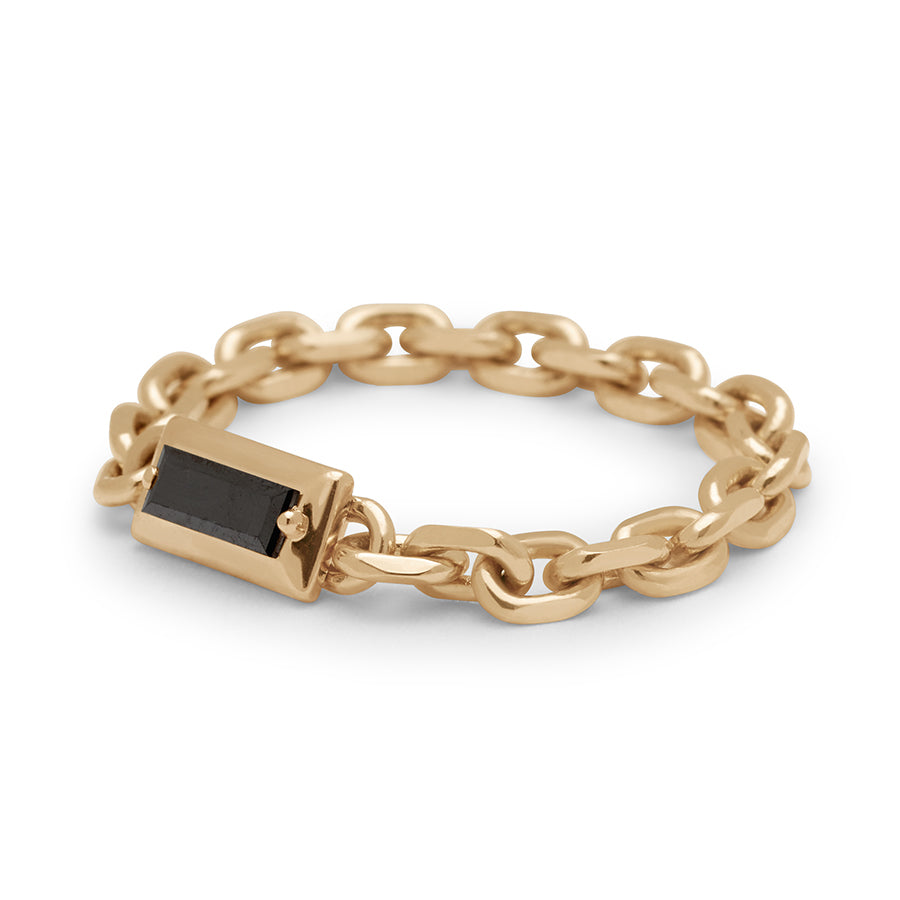 Angled view of a band with a bezel set black diamond baguette in a yellow gold chain setting.