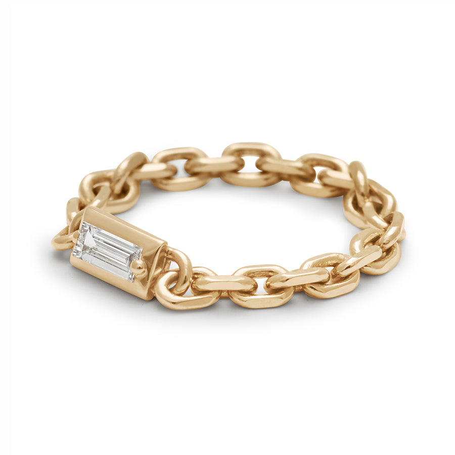 Angled view of a band with a bezel set white diamond baguette in a yellow gold chain setting.