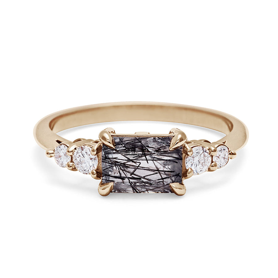 A ring with an emerald shaped black rutilated quartz center stone with two round white diamonds on either side set in yellow gold., Yellow Gold