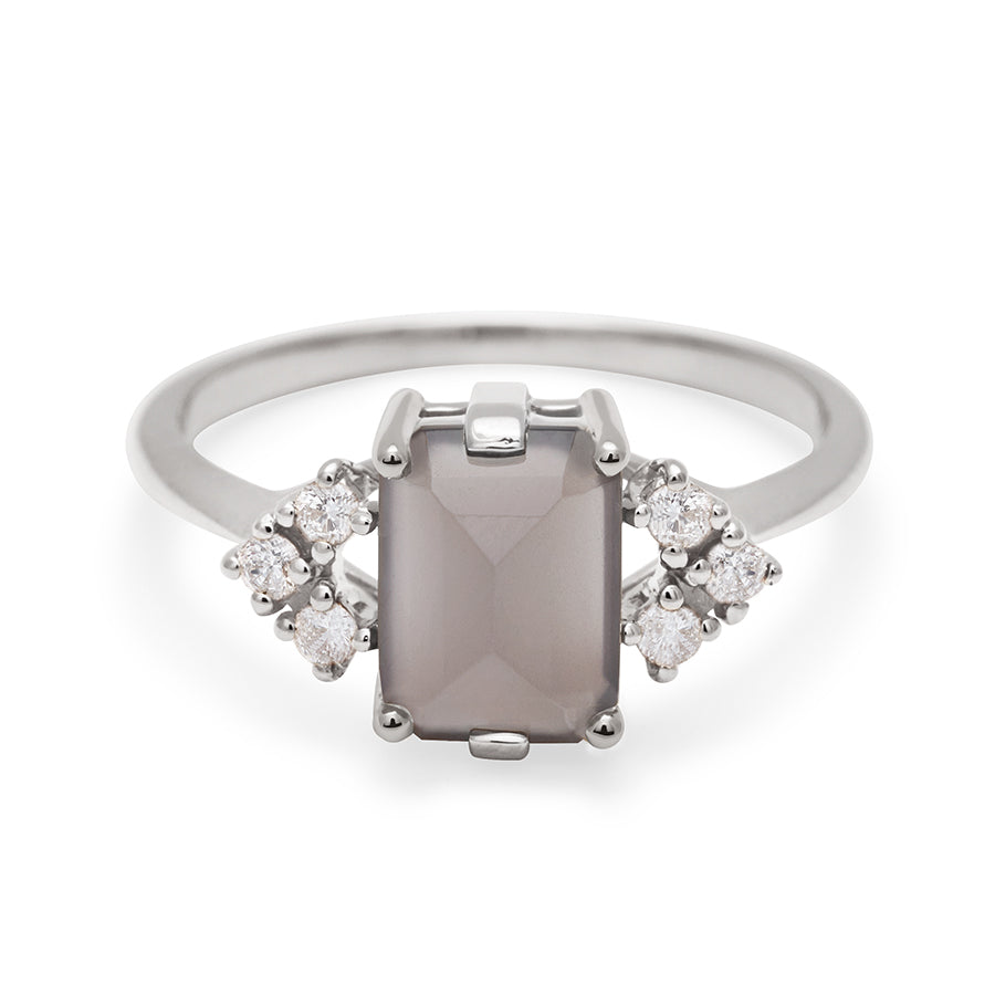 A ring with an emerald cut grey moonstone center with three round white diamonds on either side in arrow shape, set in white gold., White Gold