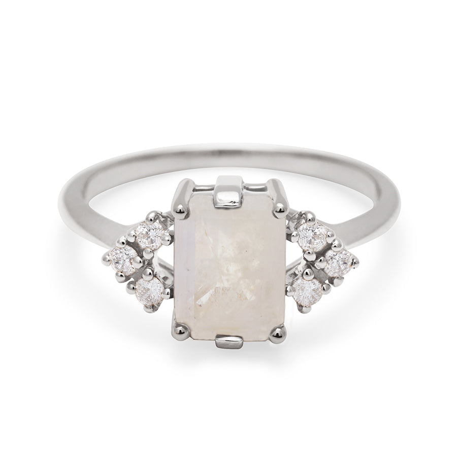 A ring with an emerald cut rainbow moonstone center with three round white diamonds on either side in arrow shape, set in white gold., White Gold