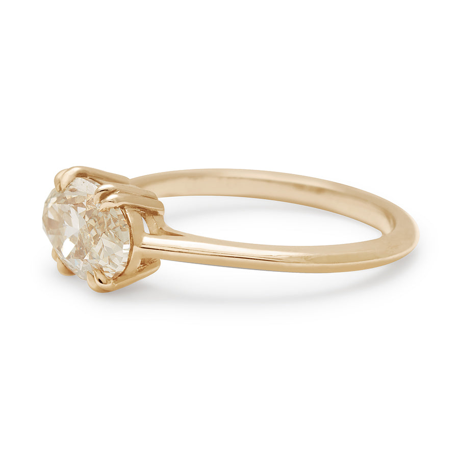 Angled view east/west solitaire ring with an oval shape brilliant cut champagne diamond stone set in yellow gold.