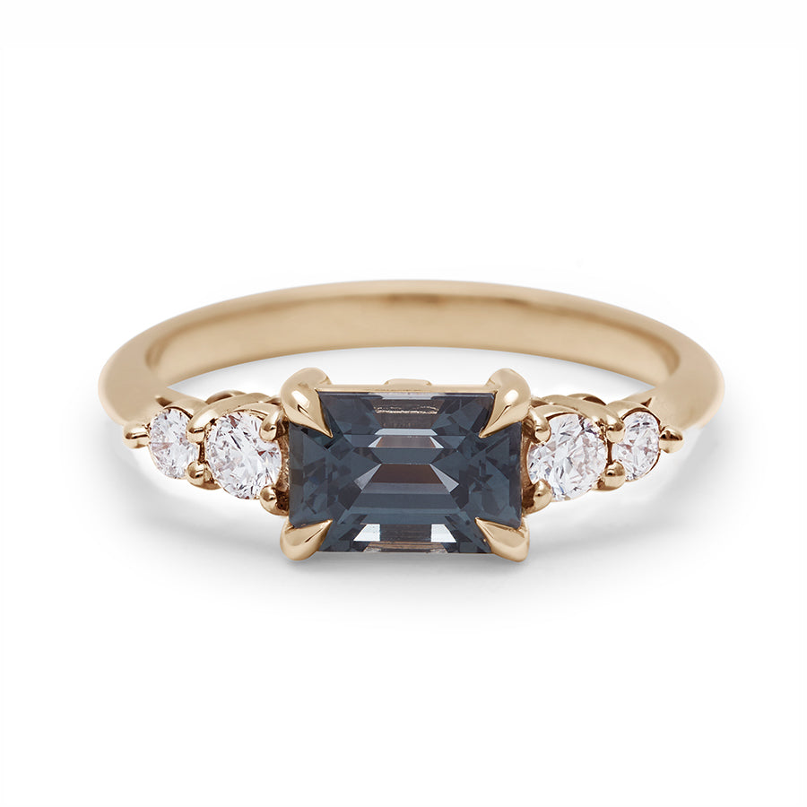 A ring with a grey spinel center stone with two white diamonds on either side set in recycled yellow gold., Yellow Gold