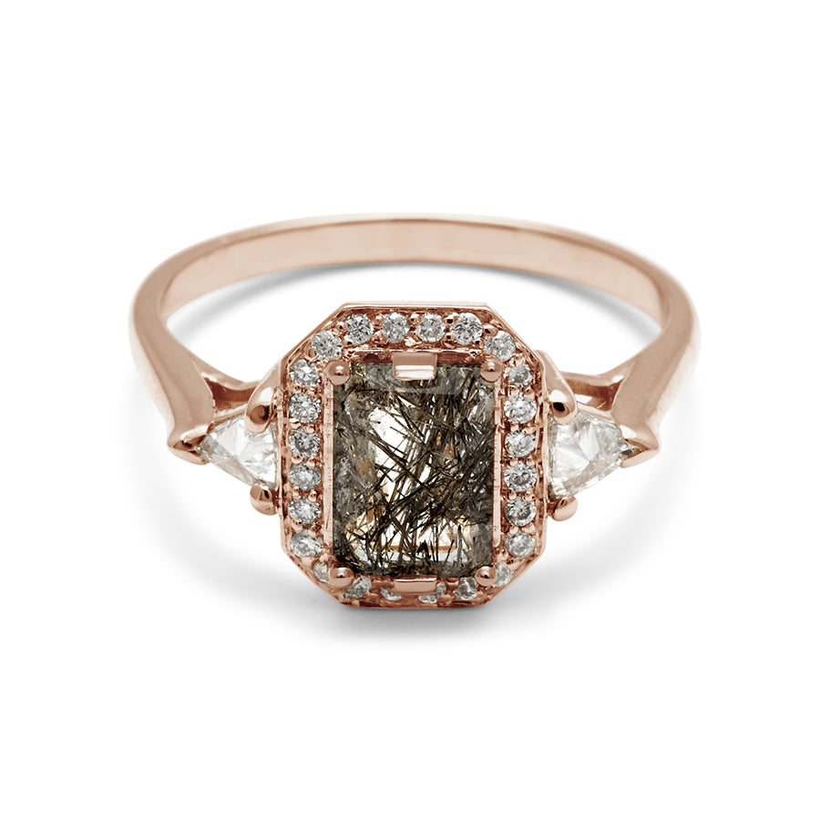 A three stone engagement ring with an emerald cut and emerald shape black rutilated quartz center stone surrounded by a white diamond pave halo with two white diamond trillion side stones set in rose gold., Rose Gold
