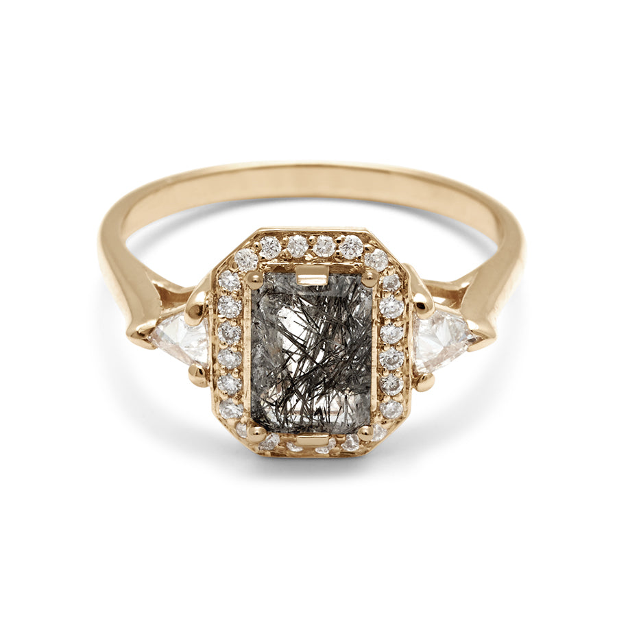 A three stone engagement ring with an emerald cut and emerald shape black rutilated quartz center stone surrounded by a white diamond pave halo with two white diamond trillion side stones set in yellow gold., Yellow Gold