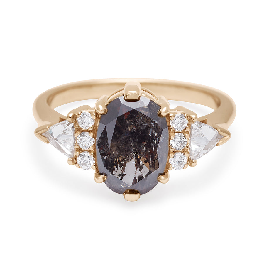 An oval shape 1.38ct grey diamond center stone ring with three round white diamonds on either and two white diamond trillions on the outer edges of each side set in yellow gold.