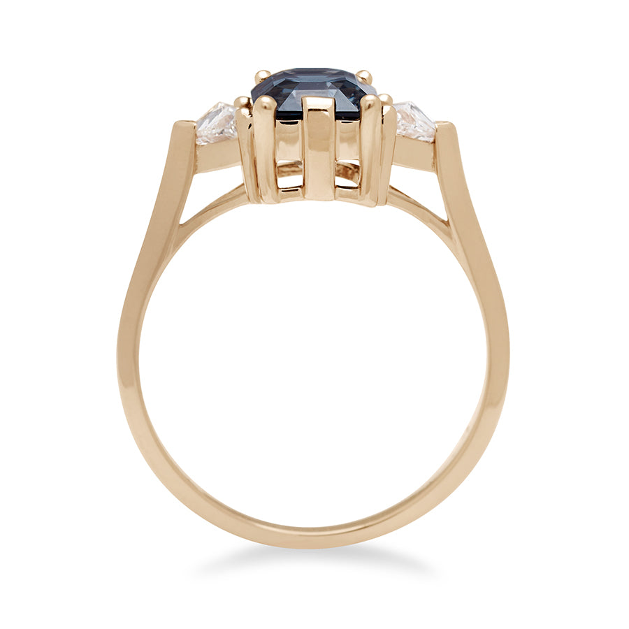 Side view of a three stone engagement ring with an emerald cut and emerald shape grey spinel center stone with two white diamond trillion side stones set in yellow gold., Yellow Gold