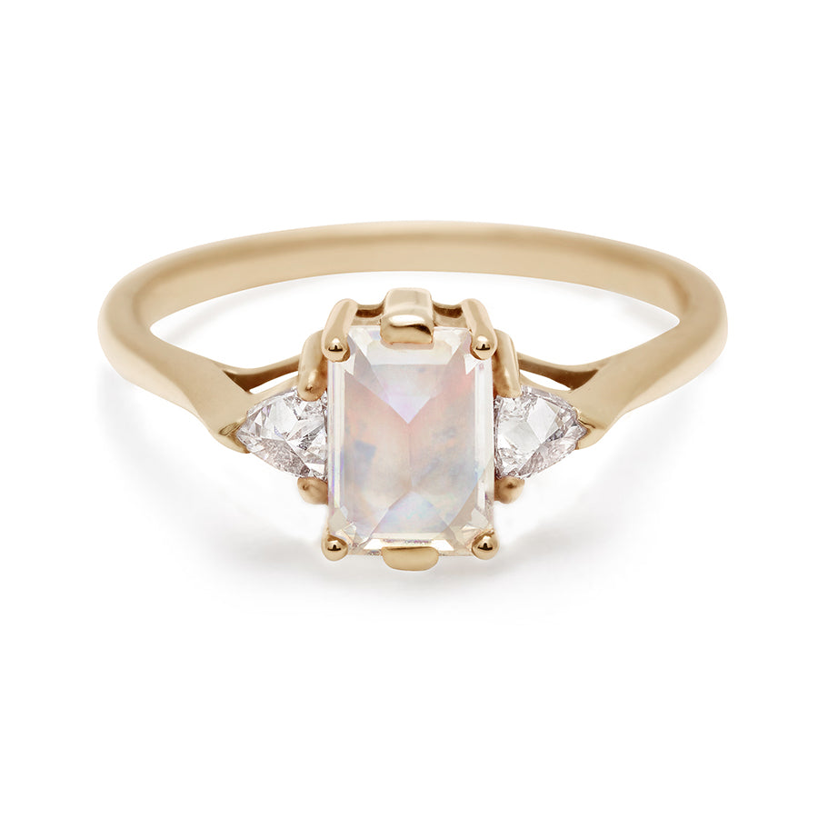 A three stone engagement ring with an emerald cut and emerald shape 7x5mm rainbow moonstone center stone with two white diamond trillion side stones set in yellow gold., Yellow Gold