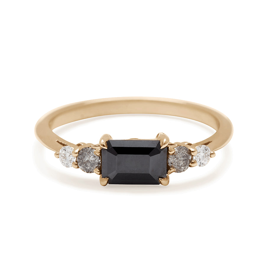 A ring with an emerald cut and shaped black diamond center stone with one round white diamond and one round grey diamond on either side set in yellow gold., Yellow Gold