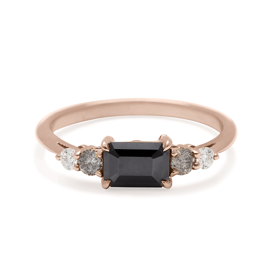 A ring with an emerald cut and shaped black diamond center stone with one round white diamond and one round grey diamond on either side set in rose gold., Rose Gold