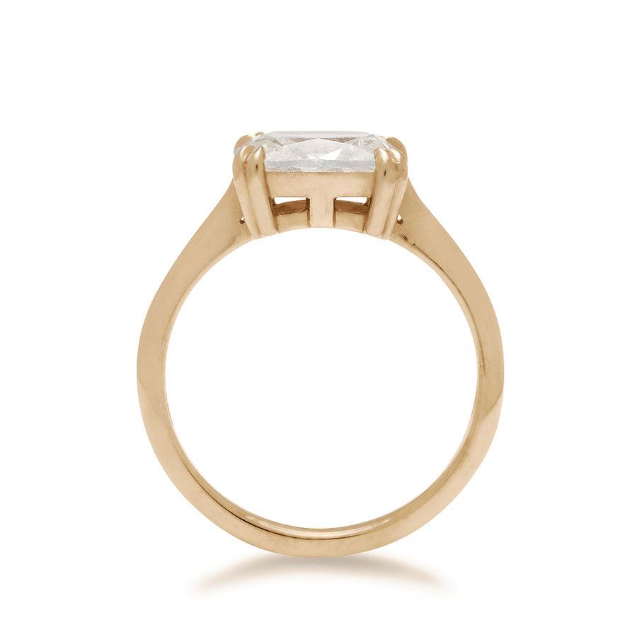 A side view of an east/west solitaire ring with a cushion cut white diamond stone set in yellow gold.