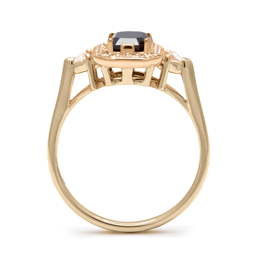 Side view of a three stone engagement ring with an emerald cut and emerald shape black diamond center stone surrounded by a white diamond pave halo with two white diamond trillion side stones set in yellow gold., Yellow Gold