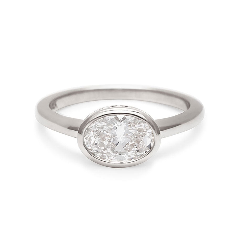 A east west oval shaped brilliant cut bezel set white diamond set in white gold., White Gold