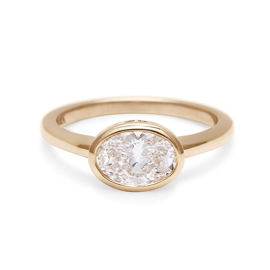 A east west oval shaped brilliant cut bezel set white diamond set in 14k yellow gold., Yellow Gold