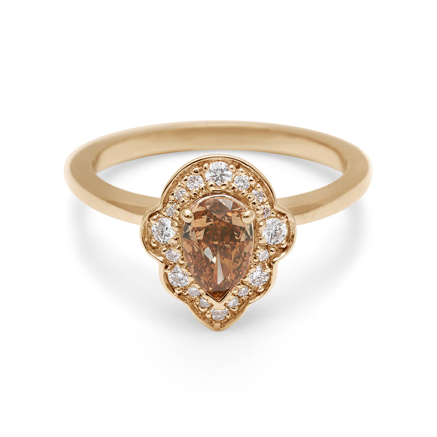 A pear shaped champagne diamond ring set in a halo of white diamonds and in yellow gold.