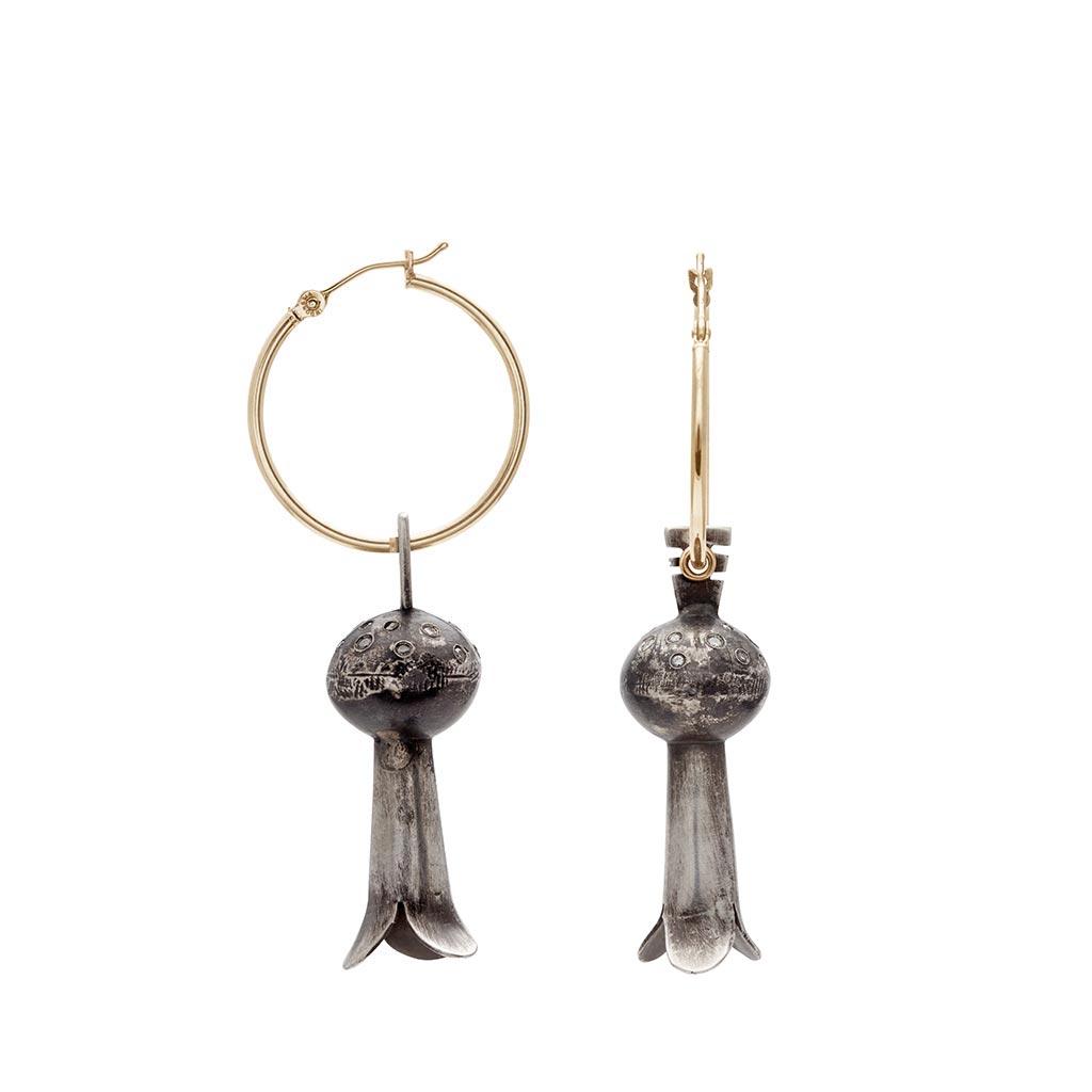 A pair of yellow gold hoops with sterling silver squash blossom charm drop portions one earring angled.