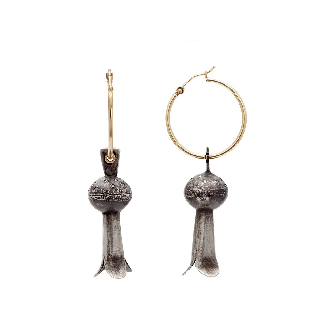 A pair of yellow gold hoops with sterling silver squash blossom charm drop portions one earring angled.