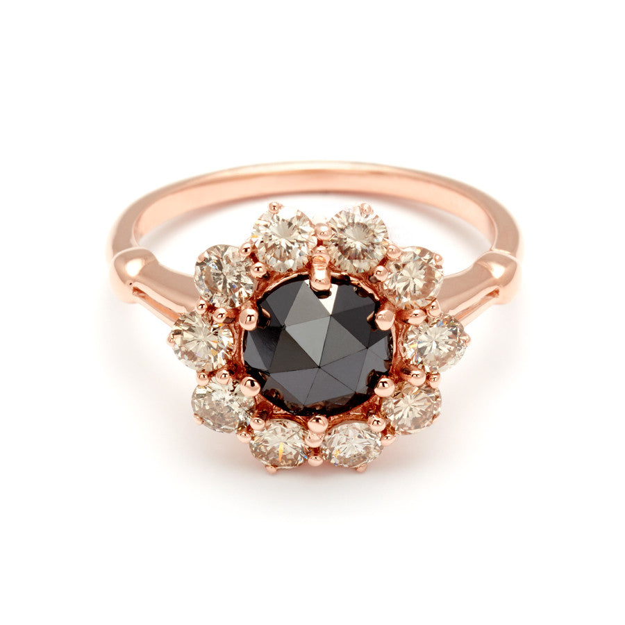 A ring with a rose cut black diamond center stone surrounded by round champagne diamonds set in rose gold.