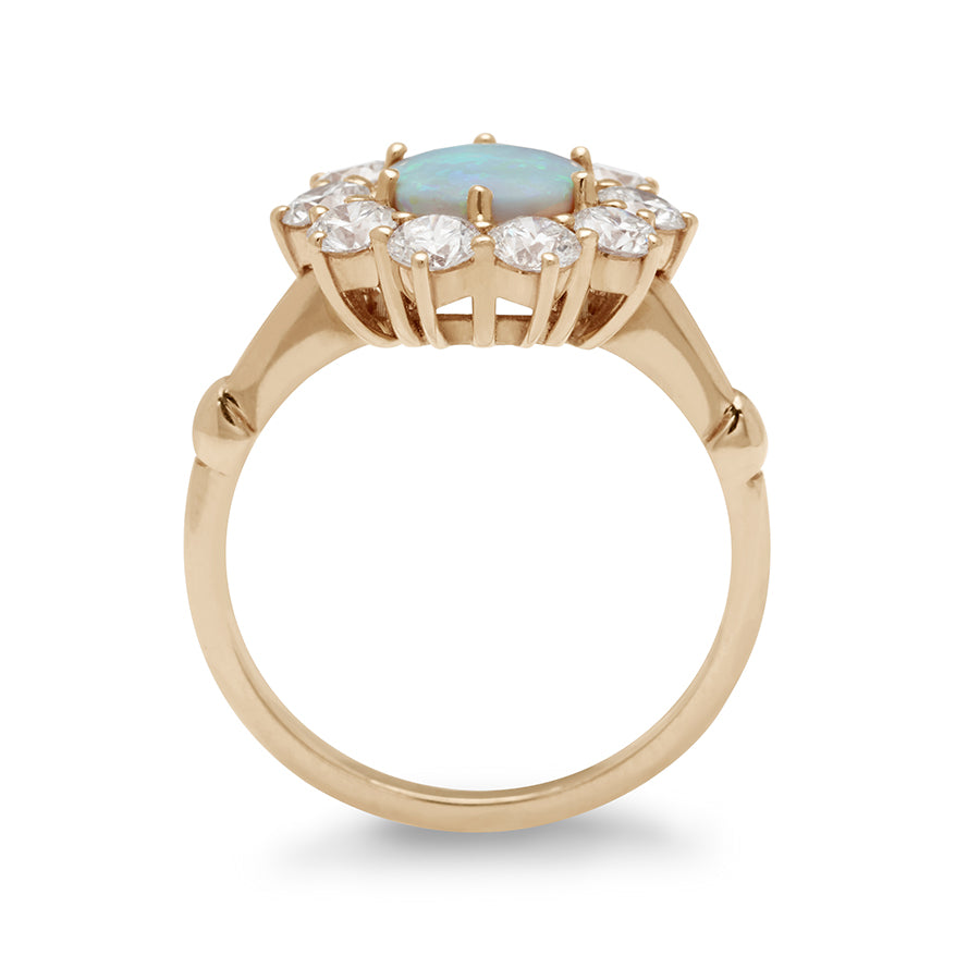 Side view of a ring with a round opal center stone surrounded by round white diamonds set in a yellow gold band.