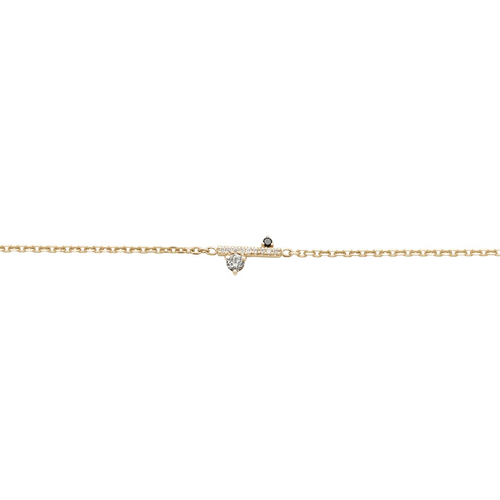 A straight line of white diamond pave with grey and black diamond accent stones on either side set in a yellow gold chain bracelet.