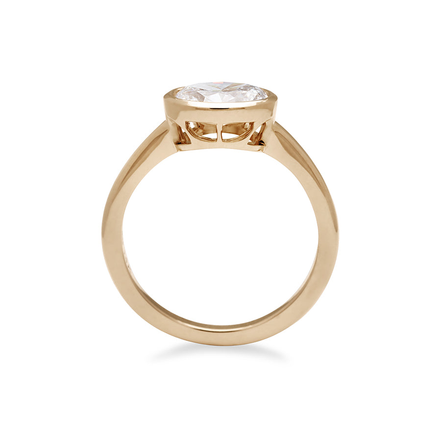 A side view of a east west oval shaped brilliant cut bezel set white diamond set in 14k yellow gold., Yellow Gold