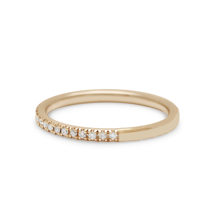 Angled view of a straight band with white diamond pave 3/4 of the way around the band set in yellow gold.