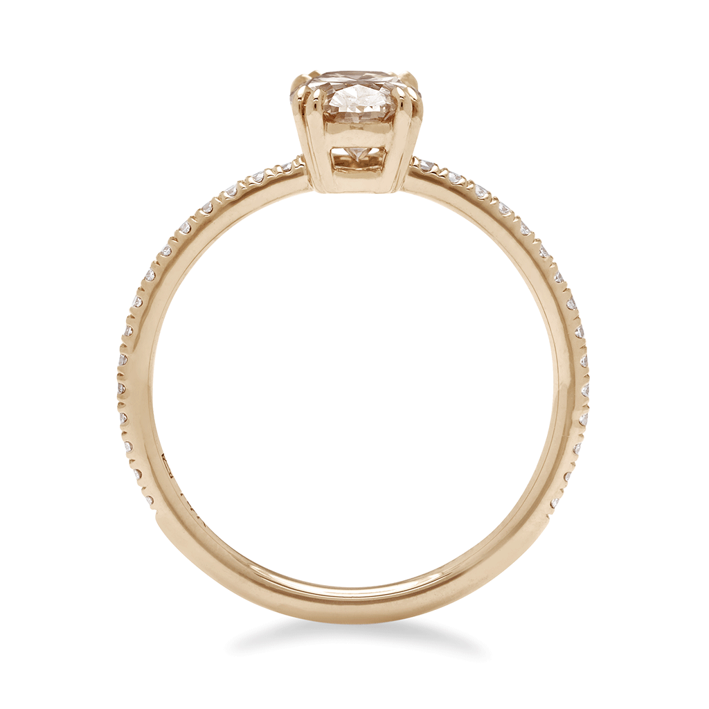 Side view of a solitaire oval champagne diamond ring with double claw prongs with white diamond pave on the band set in yellow gold.