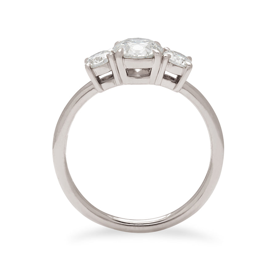 Side view of a three stone engagement ring with a round shape white diamond center stone with two round white diamond stones set in white gold.