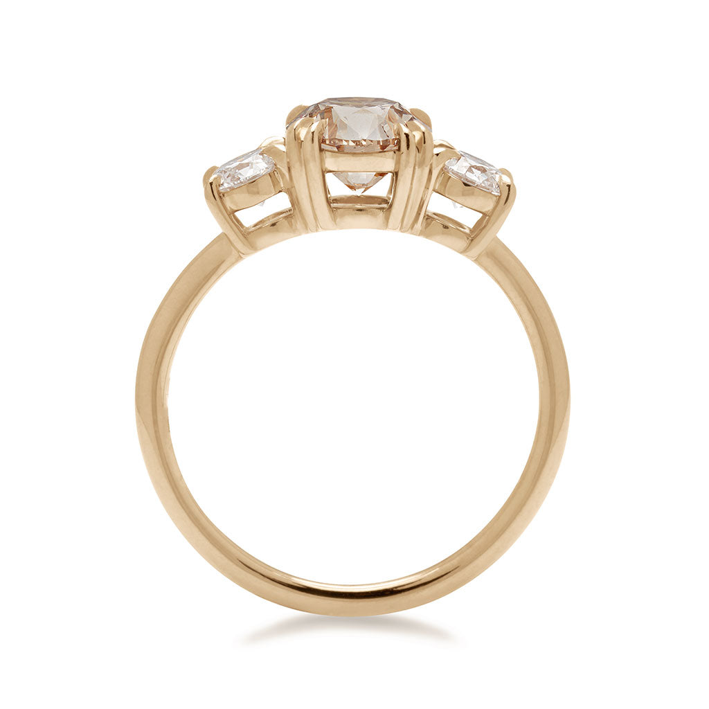 Side view of a three stone engagement ring with a round shape champagne diamond center stone with two white diamond round side stones set in yellow gold., Yellow Gold