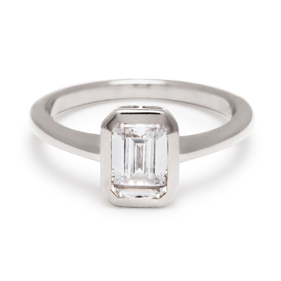A elongated emerald cut bezel set lab white diamond set in white gold., White Gold
