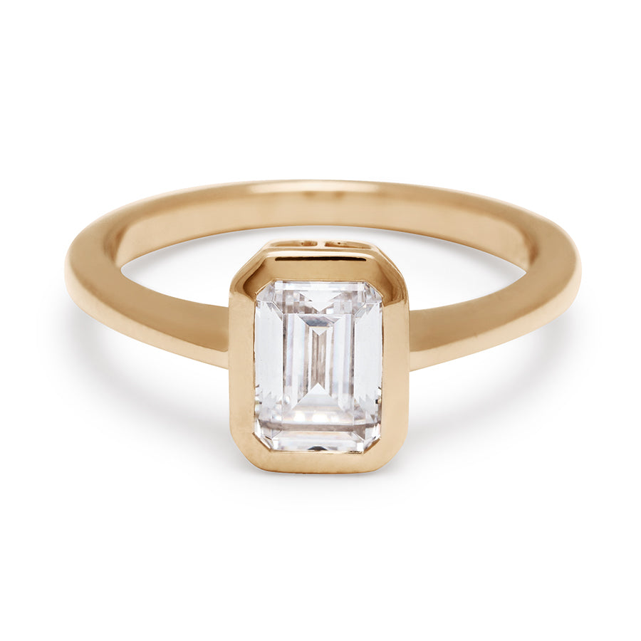 A elongated emerald cut bezel set lab white diamond set in yellow gold., Yellow Gold