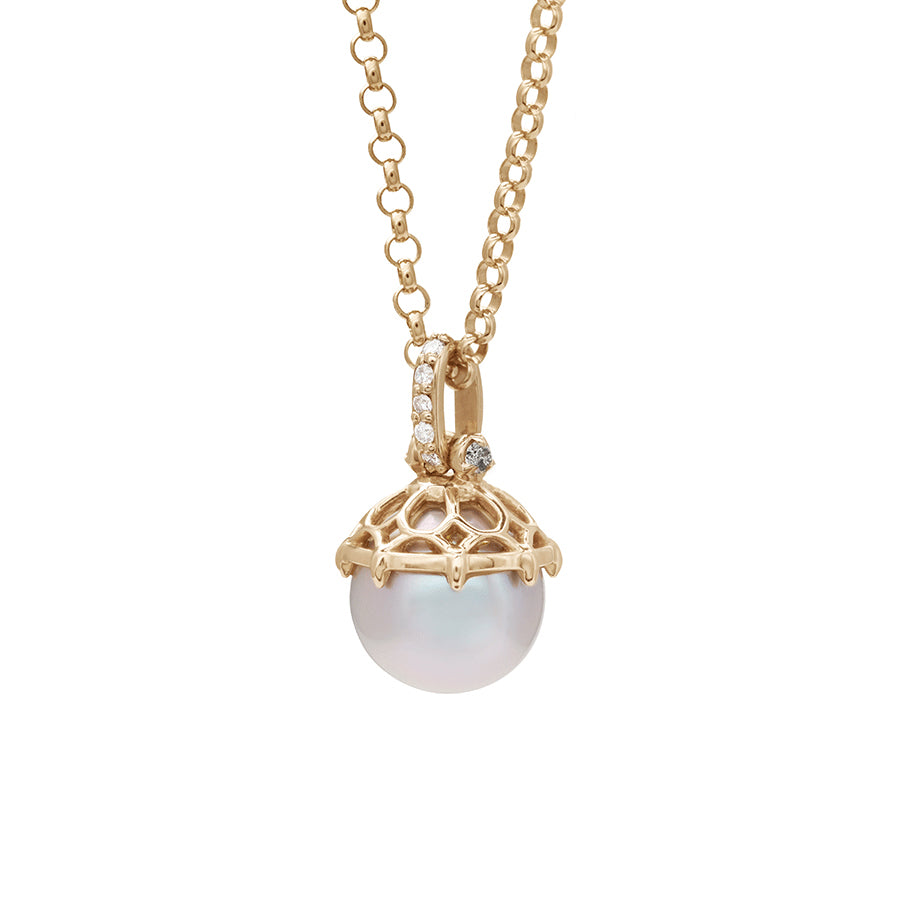 Angled view of a one of a kind light pearl pendant with white diamond pave on the top and grey diamond accent stones on either side on a yellow gold chain.
