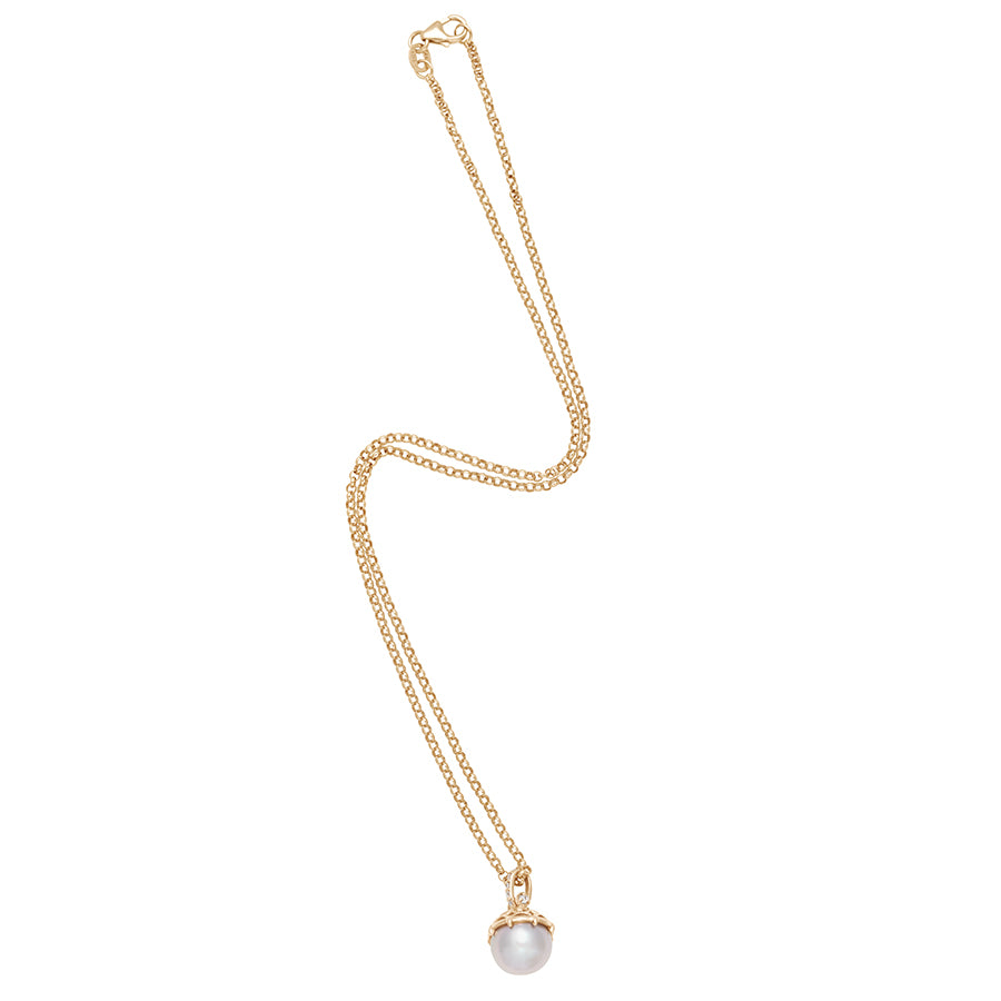 Zoomed out view of a one of a kind light pearl pendant with white diamond pave on the top and grey diamond accent stones on either side on a yellow gold chain.