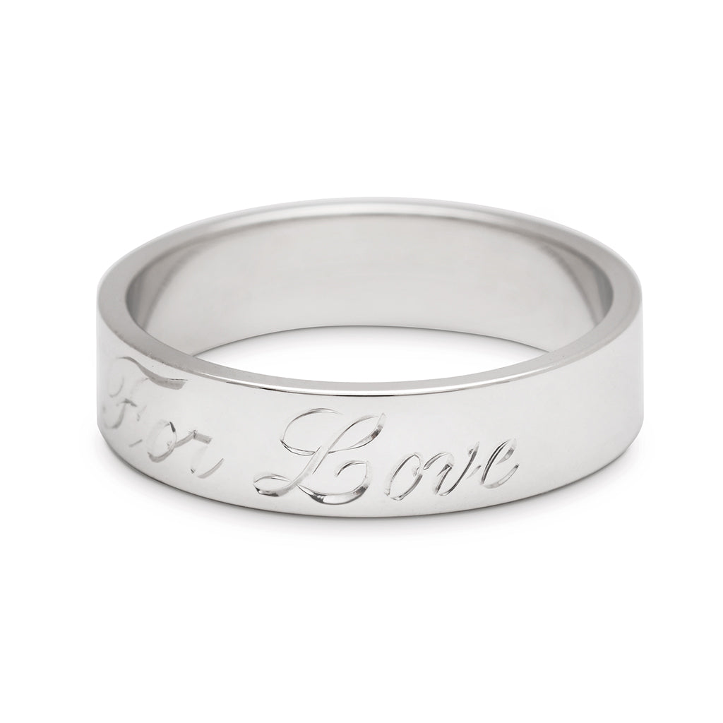 A rotated image of a white gold flat solid gold band with "All For Love" engraved on the outside.