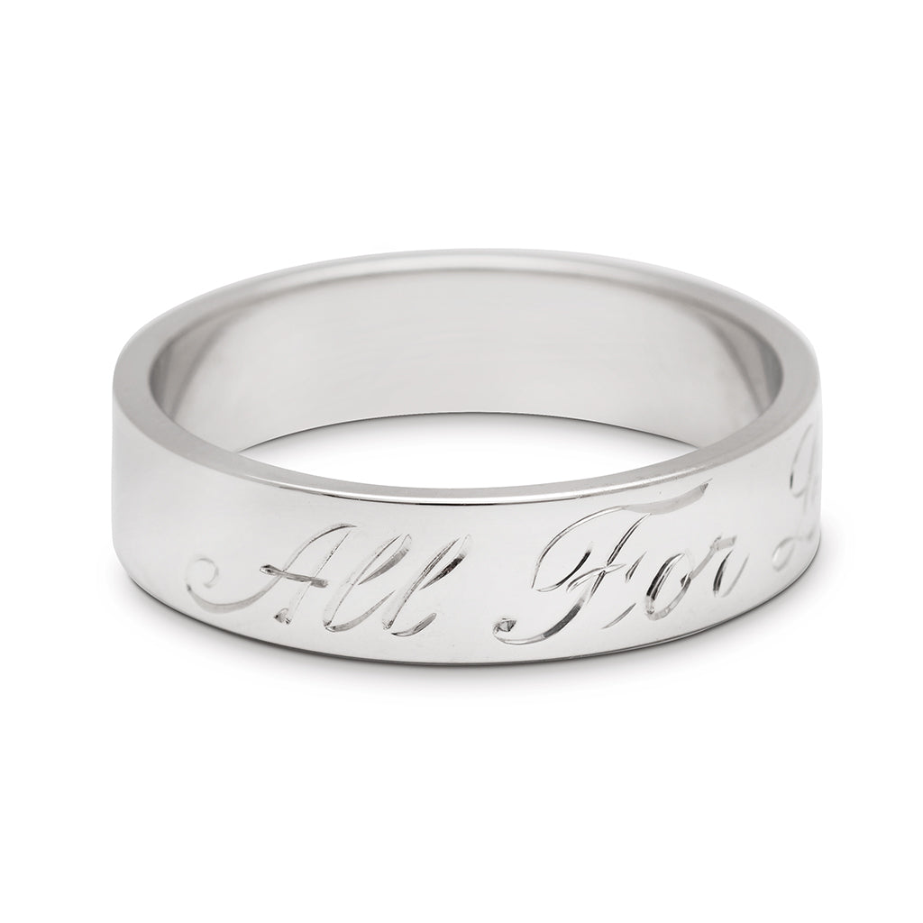 A rotated image of a white gold flat solid gold band with "All For Love" engraved on the outside.