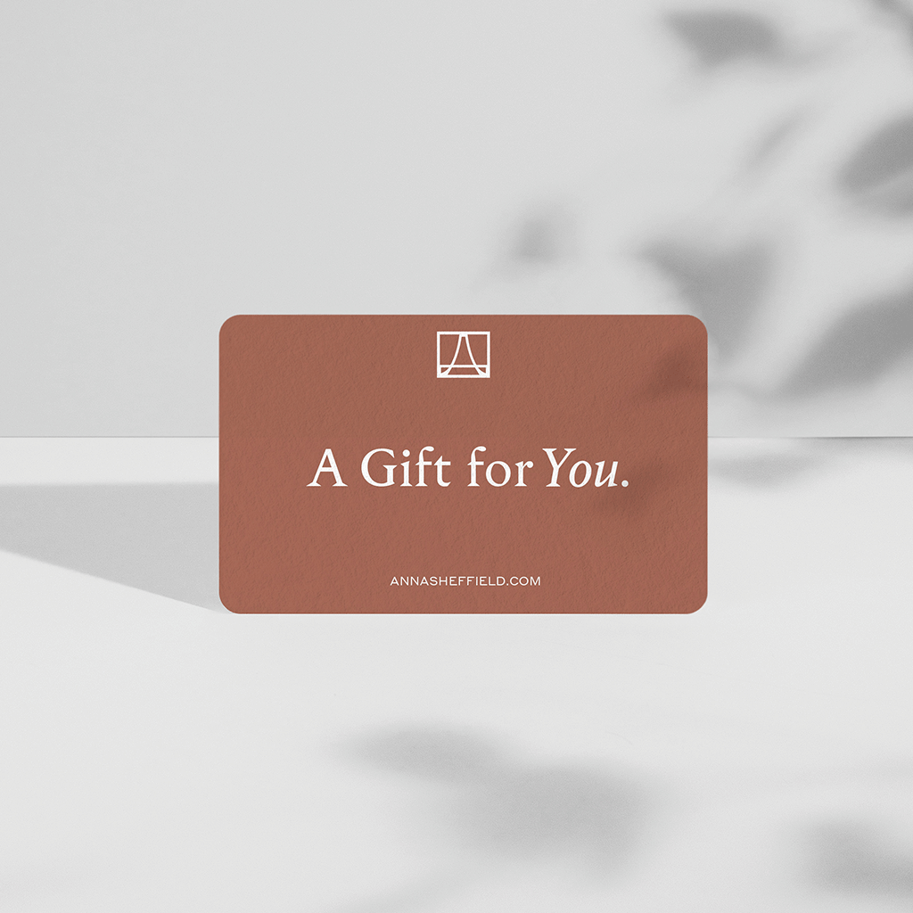 "Anna Sheffield" gift card on a adobe orange color rectangle on a grey background.