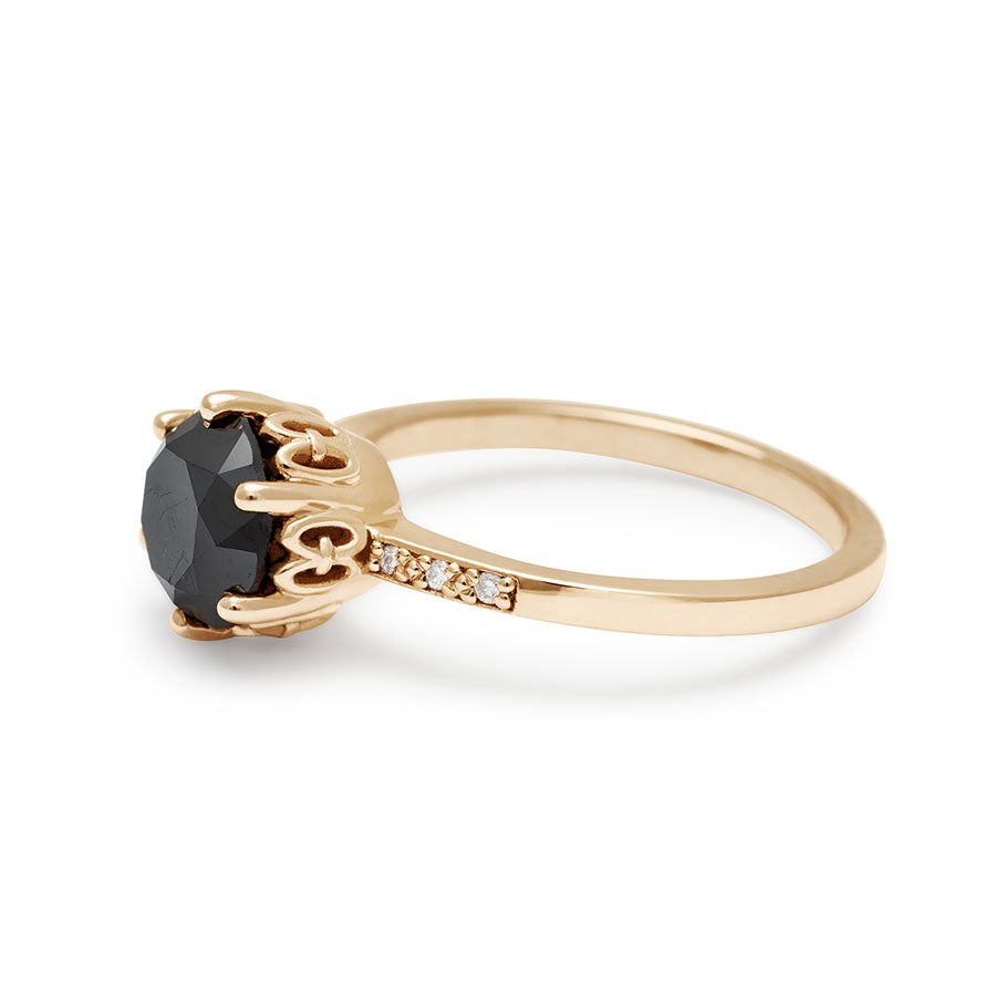 Angled view of a solitaire ring with a round 1.50ct black diamond with white diamond pave on either side set in yellow gold., Yellow Gold