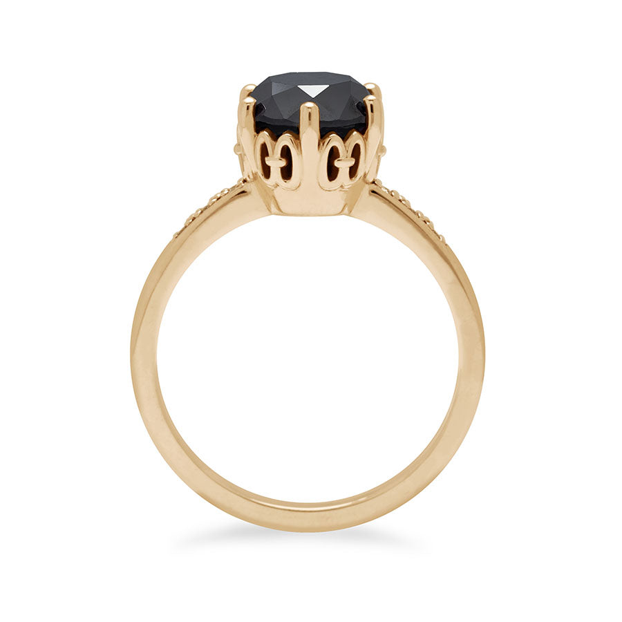 Side view of a solitaire ring with a round black diamond with white diamond pave on either side set in yellow gold.