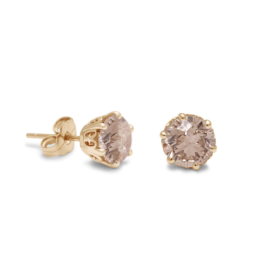 A pair of champagne diamond stud earrings set in an intricate basket in yellow gold one earring angled.