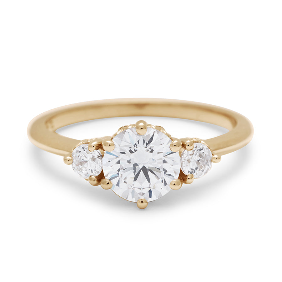 A three stone engagement ring with a round shape white diamond center stone with two white diamond round side stones set in yellow gold., Yellow Gold